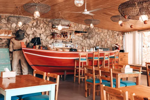 The dining room of Oyster's Seafood Bar in Batroun, with the red boat bar, stone walls and fish-trap lamps