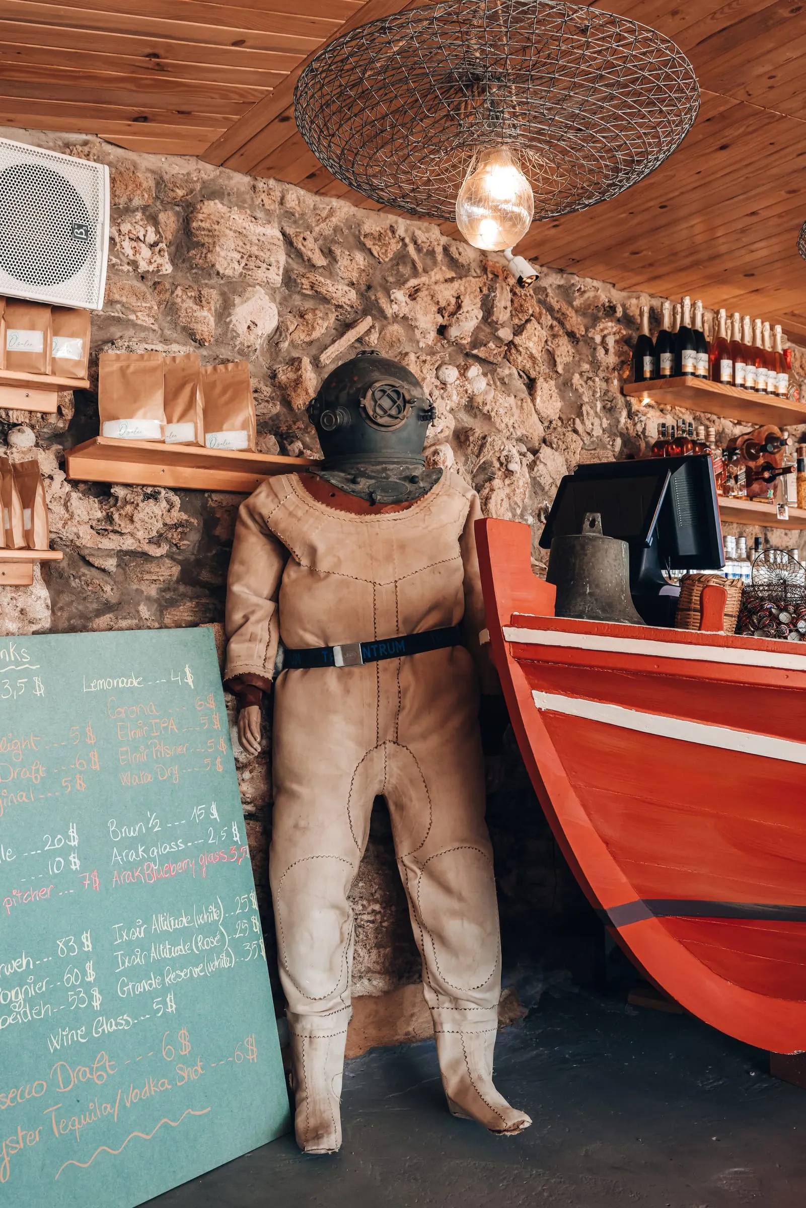 An old diving suit standing beside the red boat bar inside Oyster's Seafood Bar, Batroun