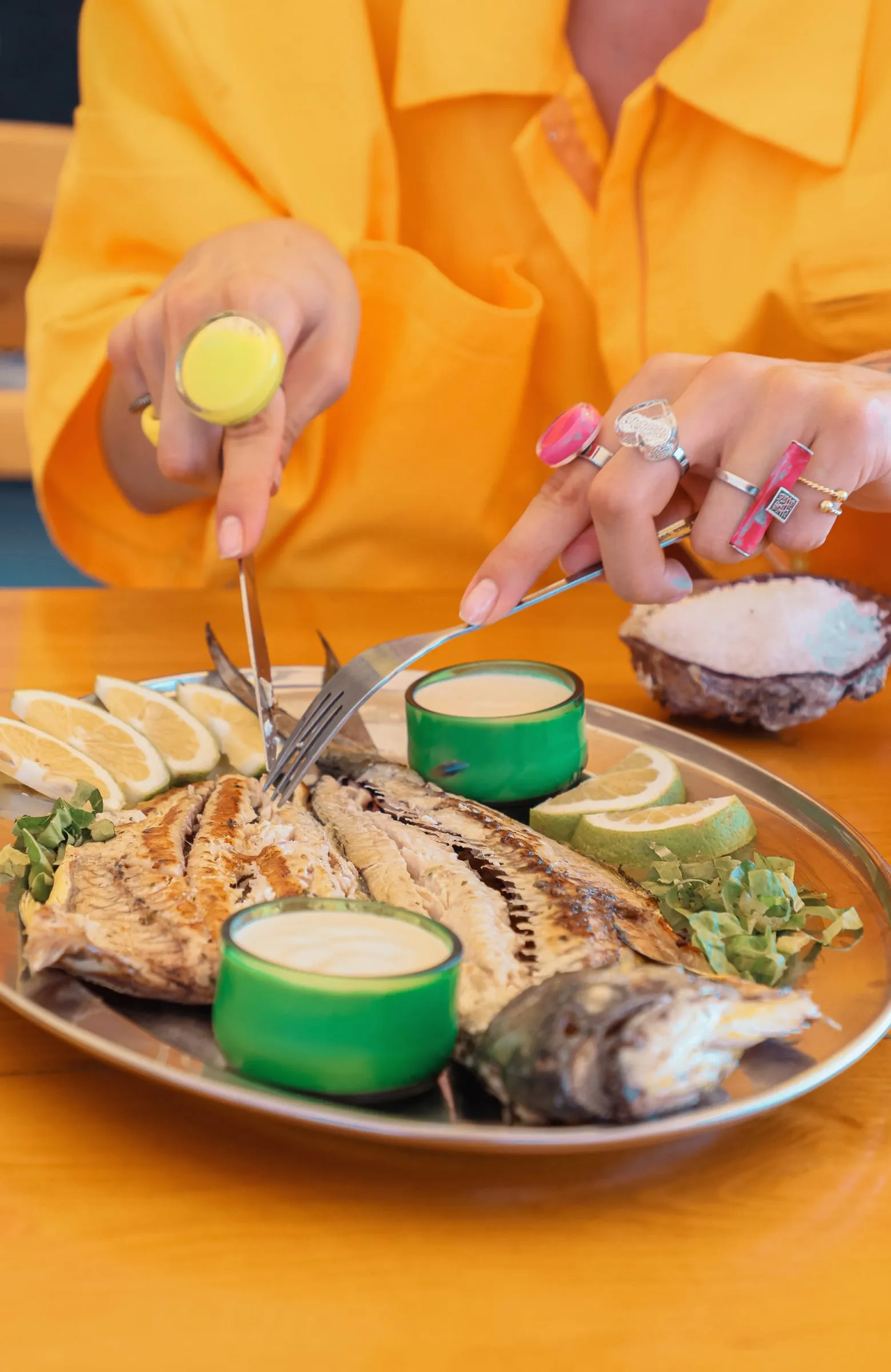 A whole grilled fish being squeezed with lemon at Oyster's Seafood Bar, Batroun