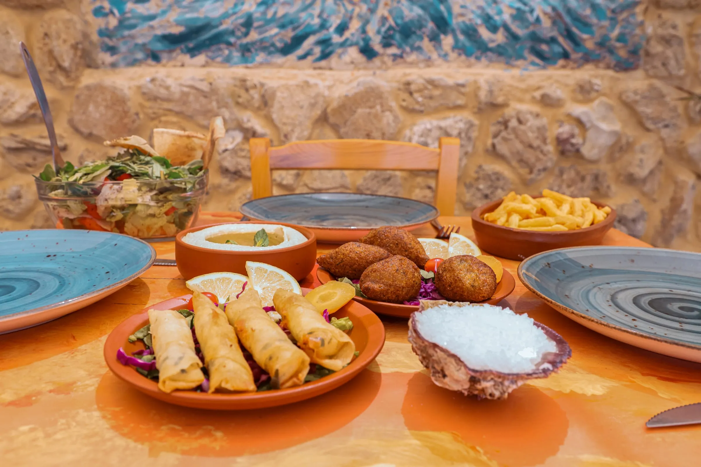 Fish kebbe, fried rolls, fries and sea salt on the turquoise table at Oyster's Seafood Bar, Batroun