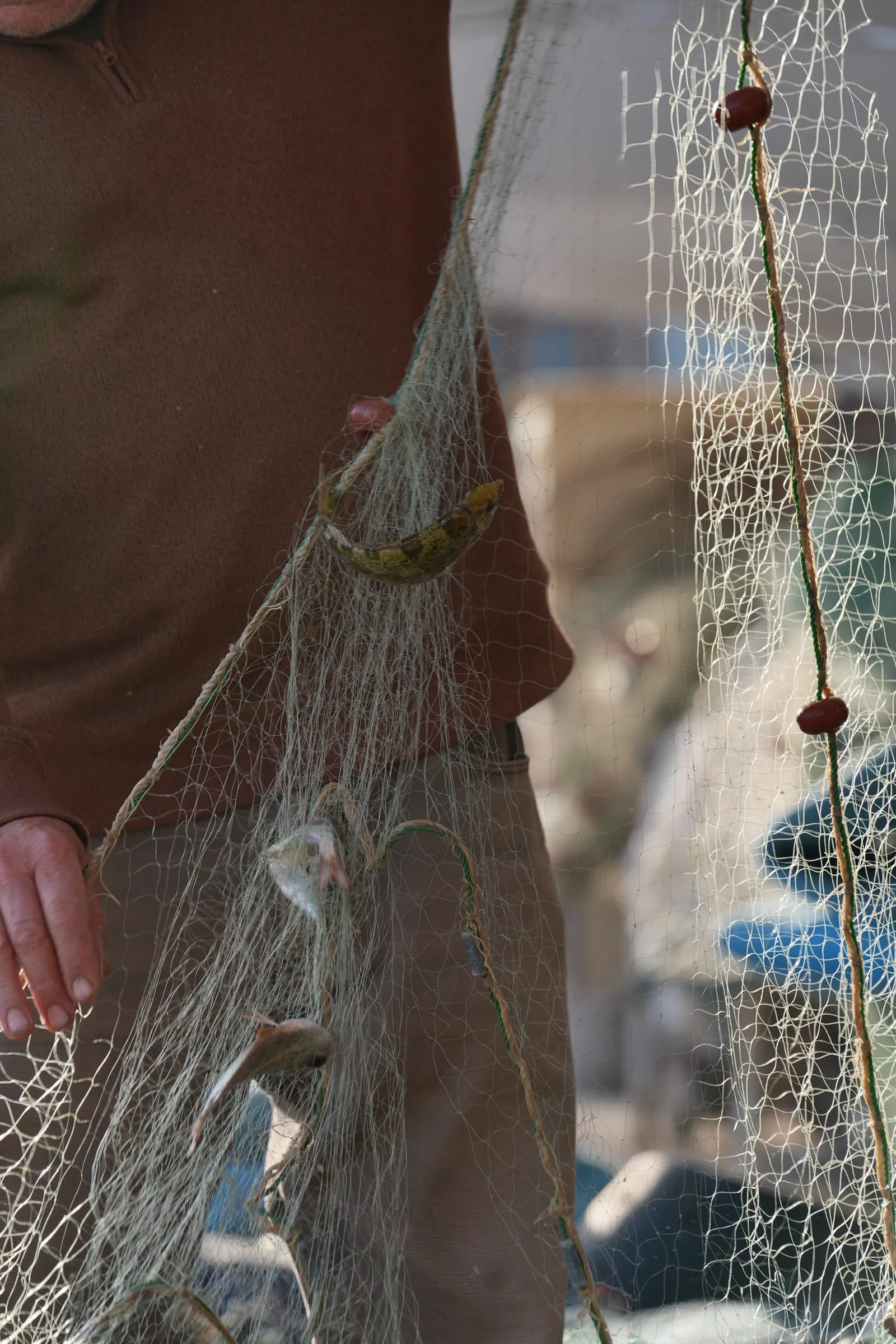 A fisherman holding a net with floats on the quay at Batroun Mina
