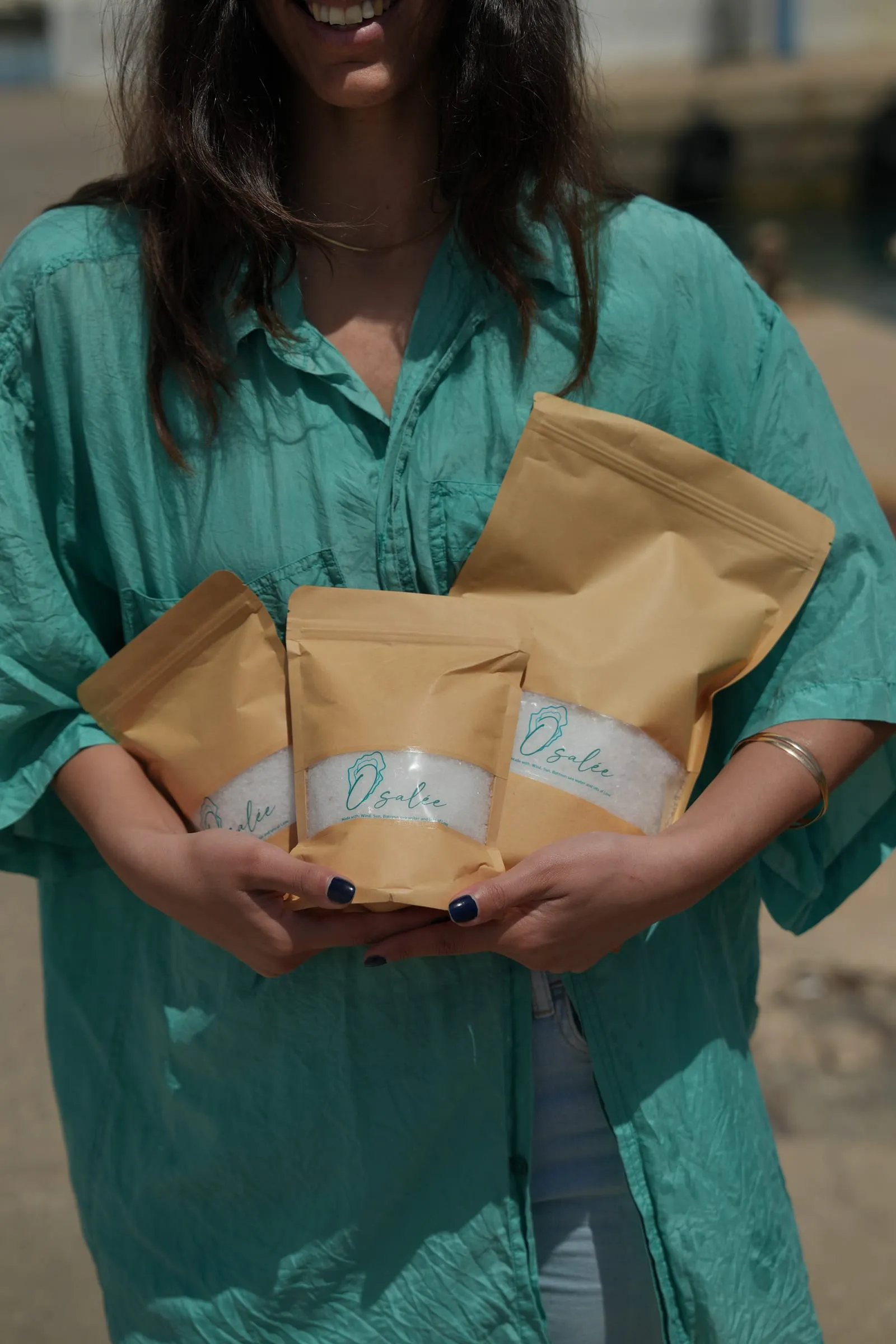 Three Osalée sea salt pouches held in the arms of a woman in a turquoise shirt