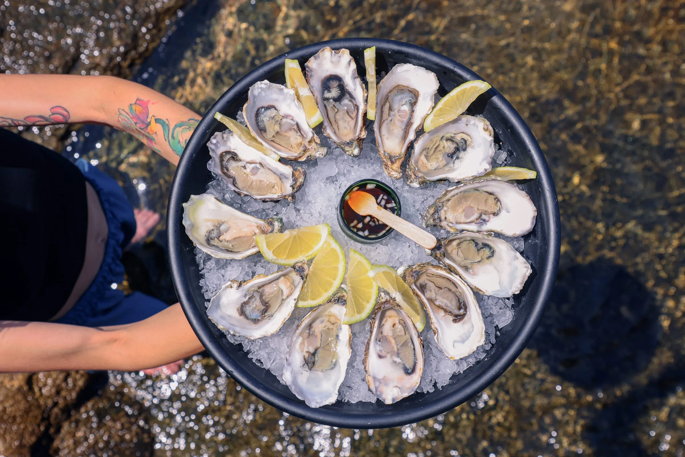 A round platter of fresh oysters on ice with lemon at Oyster's Seafood Bar, Batroun Mina, seen from above