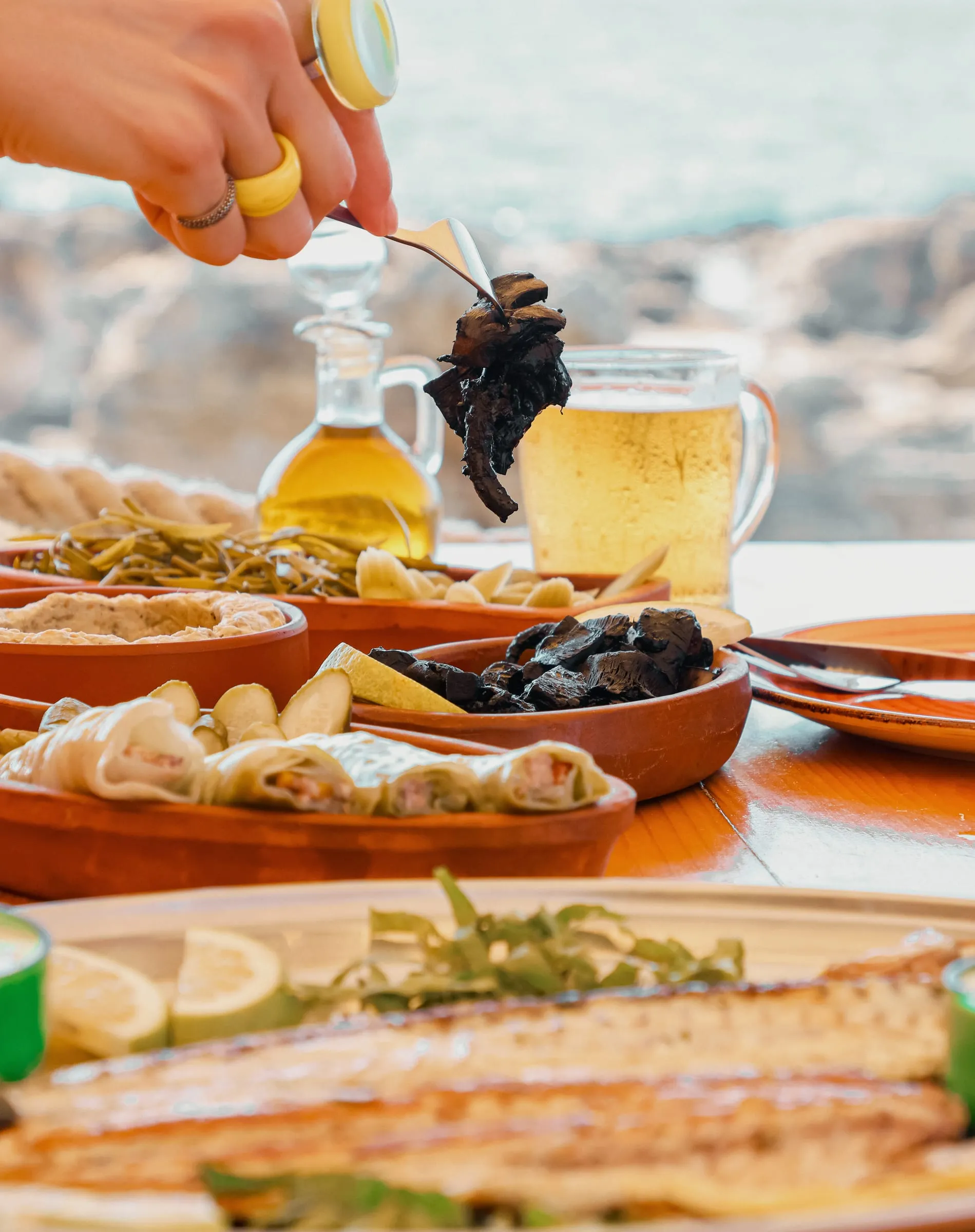 A drink being poured from a jug over a long table of seafood