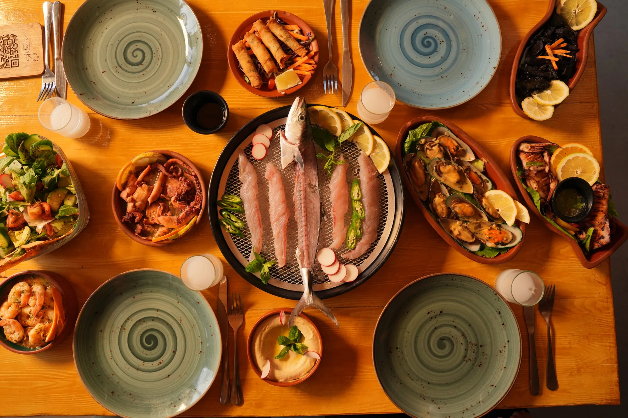 A full table at Oyster's Seafood Bar in Batroun seen from above: whole fish, mezze, salads and plates