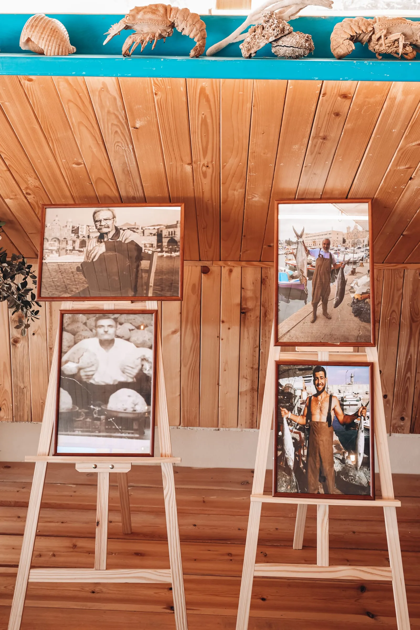 Black and white portraits of fishermen on easels against a wooden wall at Oyster's Seafood Bar, Batroun